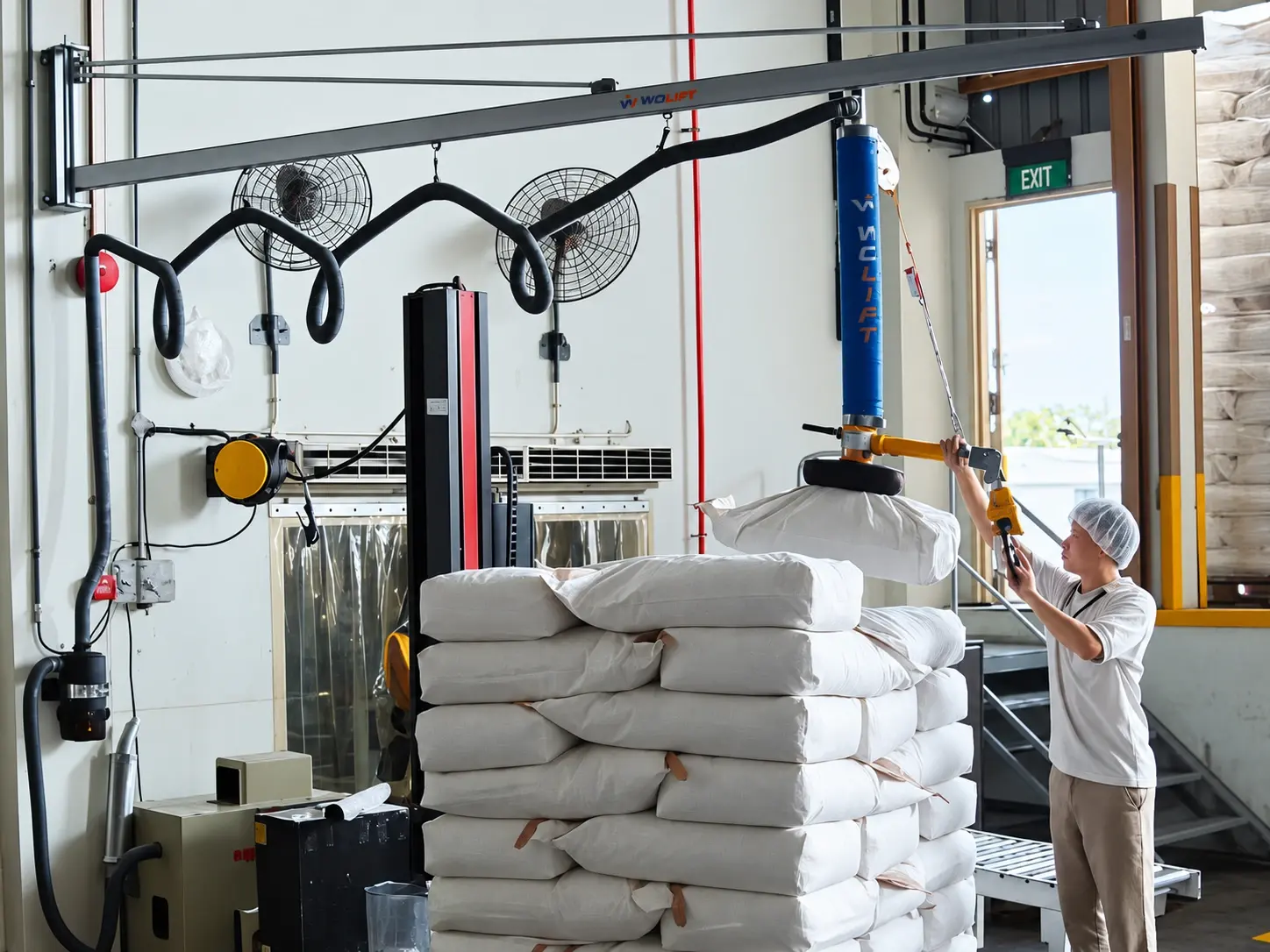 WOLIFT vacuum tube lifter handling fertilizer bags in a warehouse depalletizing station