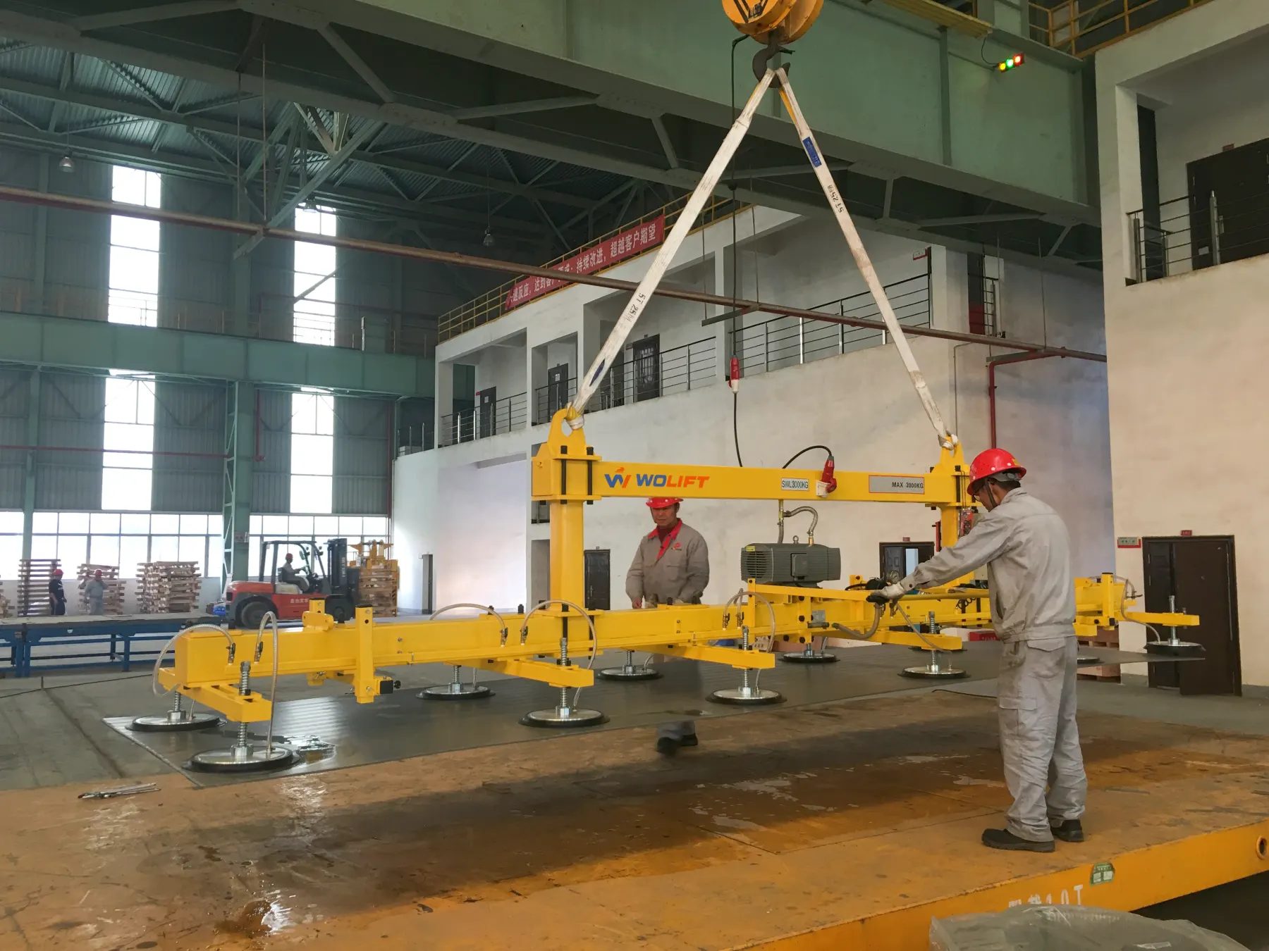 WOLIFT electric vacuum sheet metal lifter handling heavy metal plates in an industrial workshop