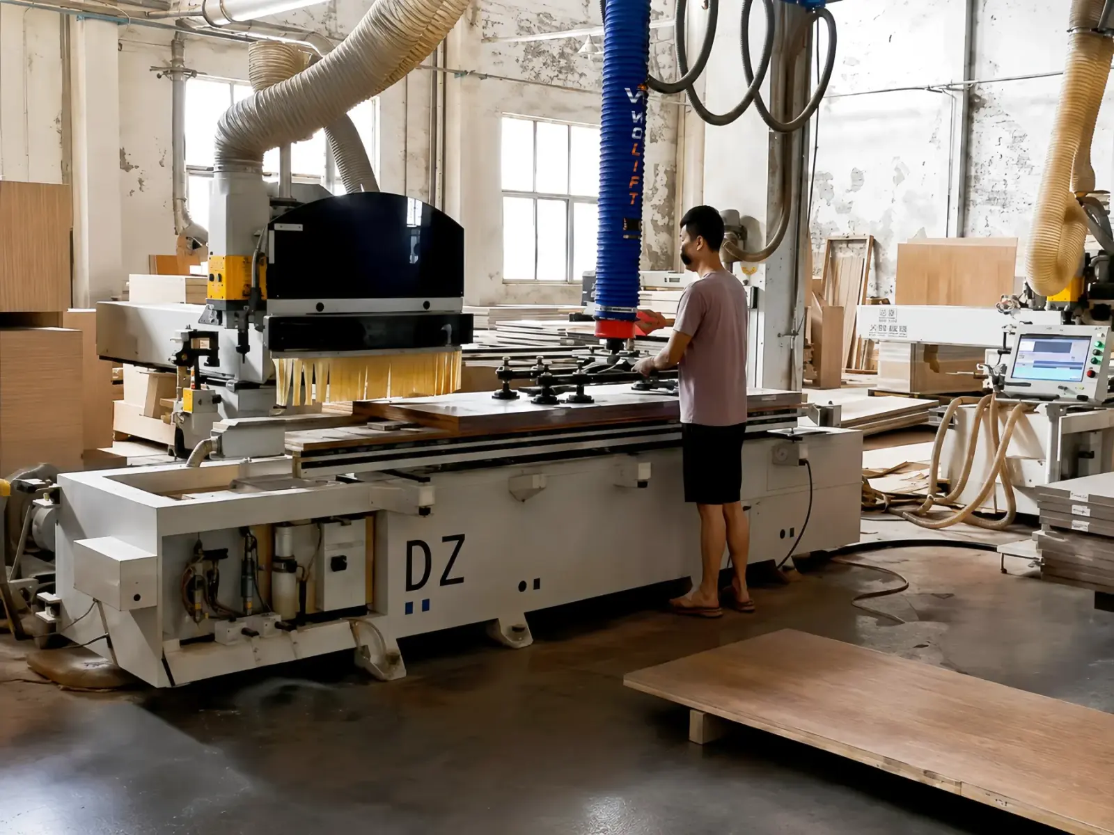 WOLIFT vacuum tube lifter loading wooden boards at a CNC machining center